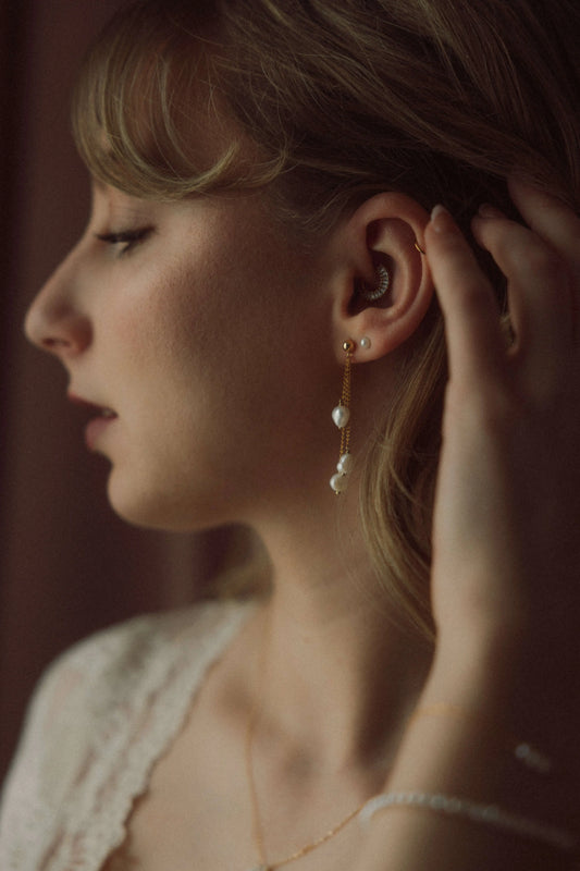Boucles d'oreilles portées avec des perles d'eau douce baroques pour un mariage